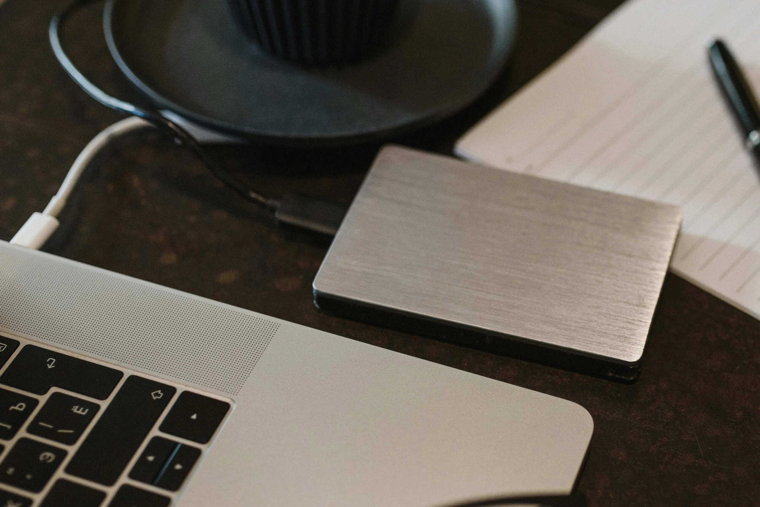 Secure Data Backup - Free Closeup of an external hard drive connected to a laptop with a USB cable on a desk. Stock Photo