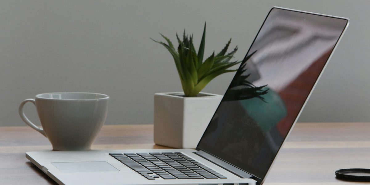 AI at work Free Minimalist home office desk with laptop, smartphone, and plant for a modern work environment. Stock Photo