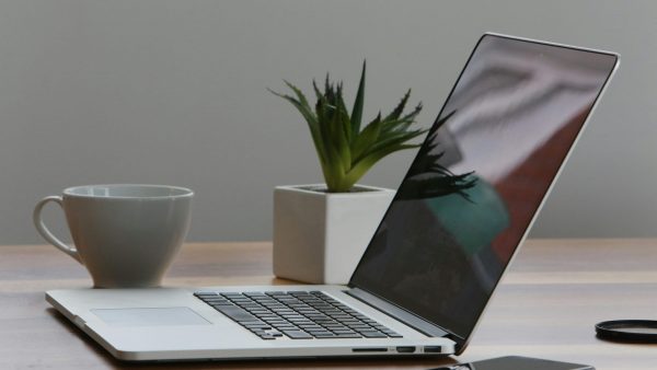 AI at work Free Minimalist home office desk with laptop, smartphone, and plant for a modern work environment. Stock Photo