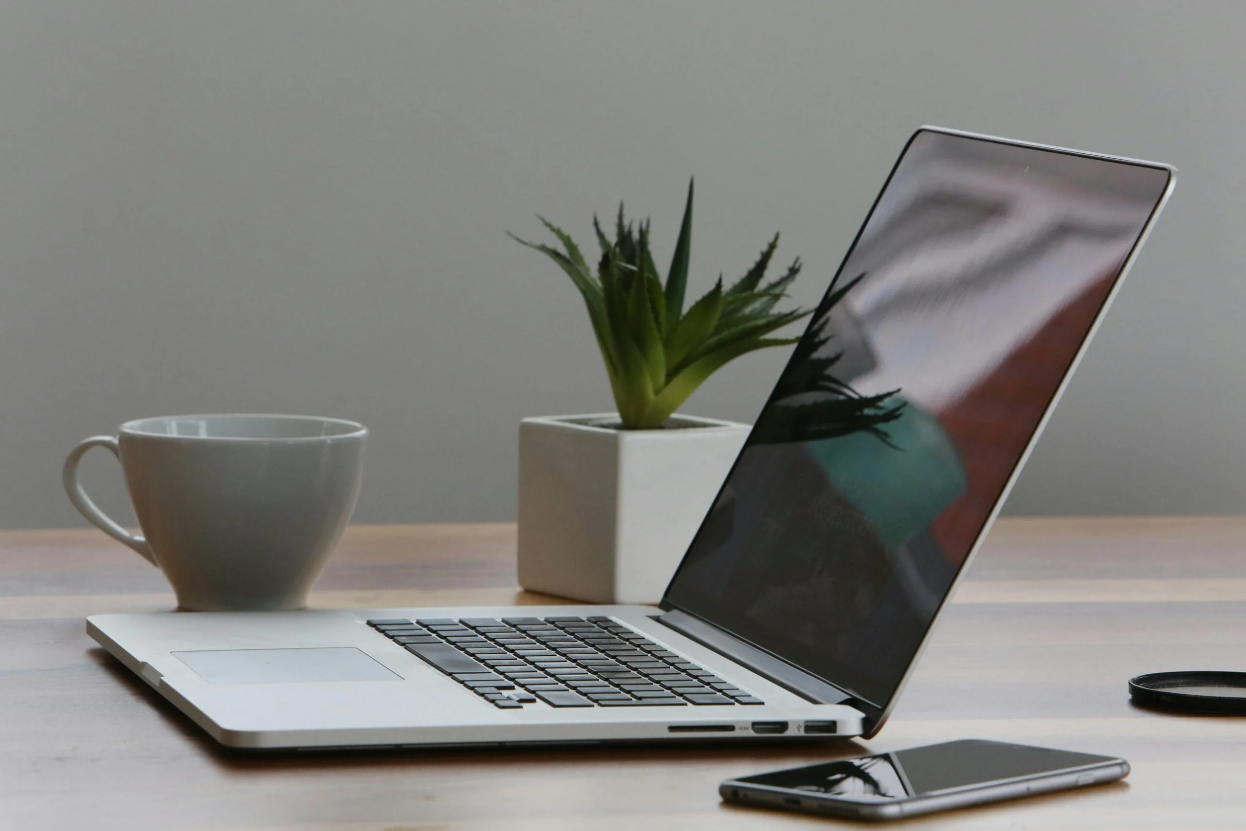 AI at work Free Minimalist home office desk with laptop, smartphone, and plant for a modern work environment. Stock Photo