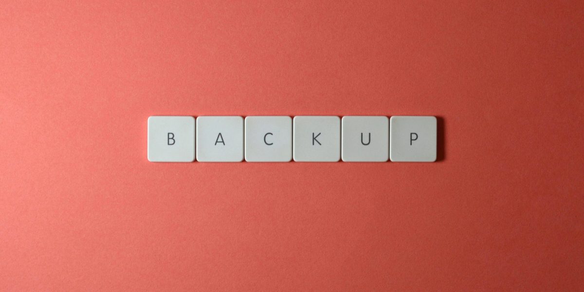 Backup and Recovery Plans Free Close-up of keyboard keys spelling 'BACKUP' placed on a coral-colored surface. Stock Photo