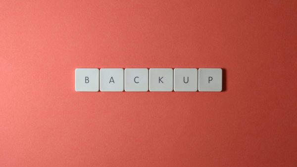 Backup and Recovery Plans Free Close-up of keyboard keys spelling 'BACKUP' placed on a coral-colored surface. Stock Photo