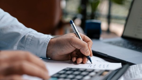 growth tech stack Free A person calculating finances with a calculator and pen on a desk indoors. Stock Photo