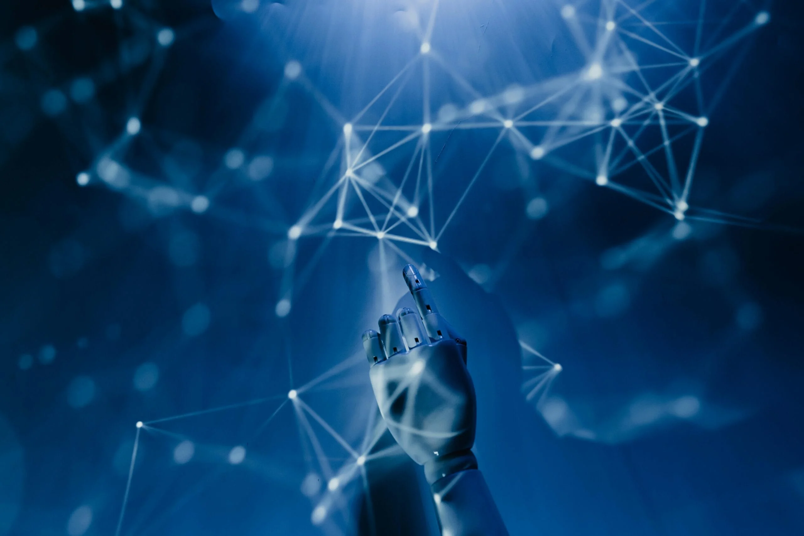 AI tools in 2025. Free A robotic hand reaching into a digital network on a blue background, symbolizing AI technology. Stock Photo