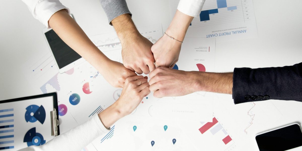 Smart IT Free Colleagues celebrate success with a fist bump over financial charts depicting teamwork and unity. Stock Photo