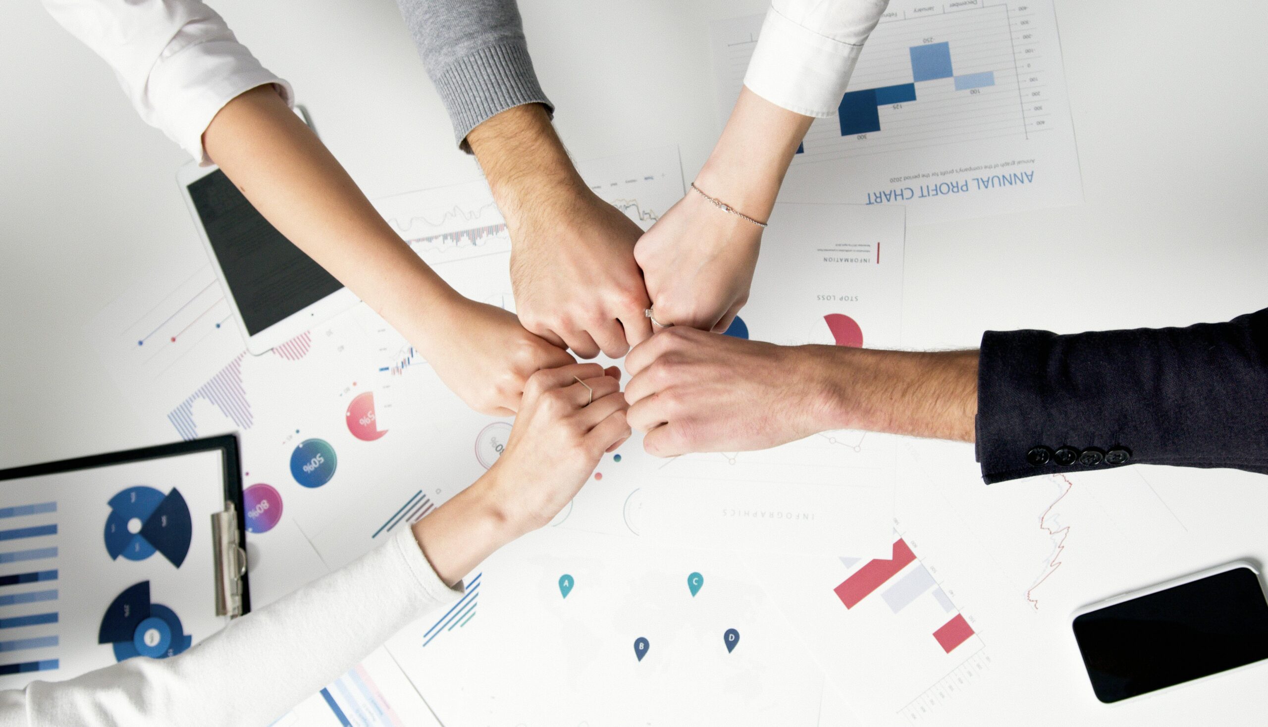 Smart IT Free Colleagues celebrate success with a fist bump over financial charts depicting teamwork and unity. Stock Photo