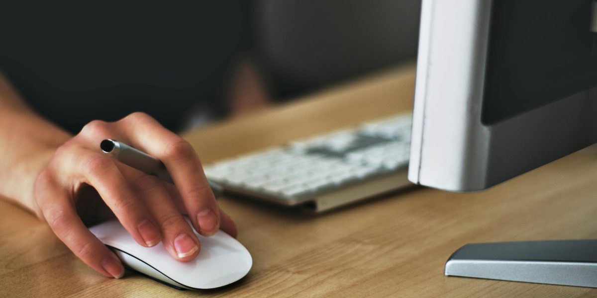 Microsoft 365 licensing Free A hand using a wireless mouse at a modern desk setup with a computer and keyboard. Stock Photo