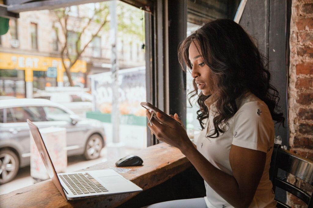 Woman using a personal laptop and smartphone at a cafe